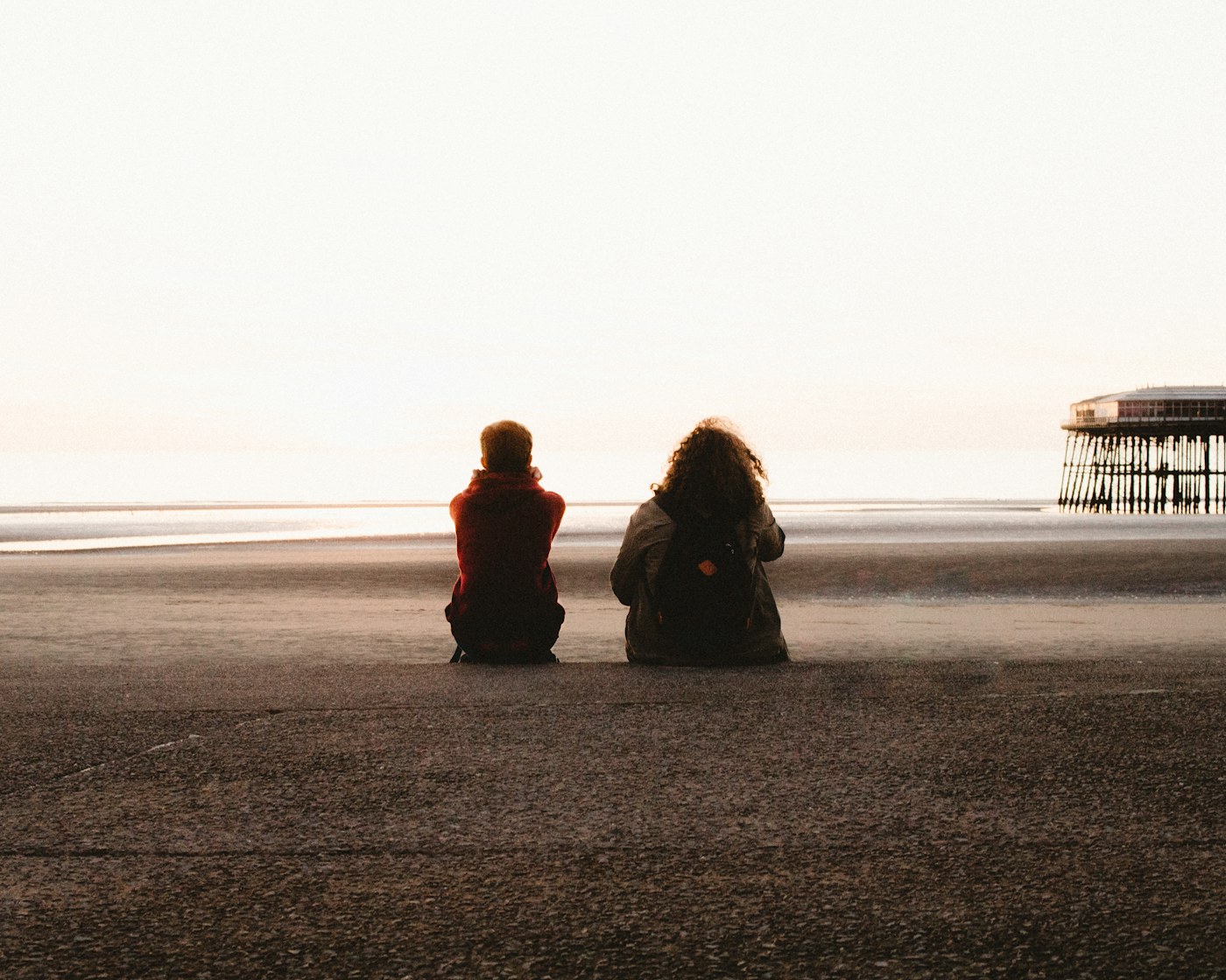 Two people sitting by the sea, watching the sunset